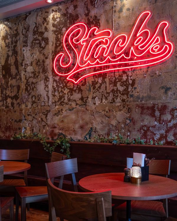 Stacks neonskylt på insidan, ovanför runda bord i matsalen