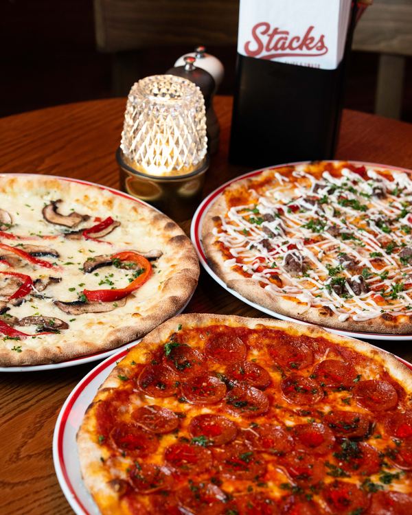 Tre vedeldade pizzor på ett bord: svamp och paprika, kebab, och pepperoni